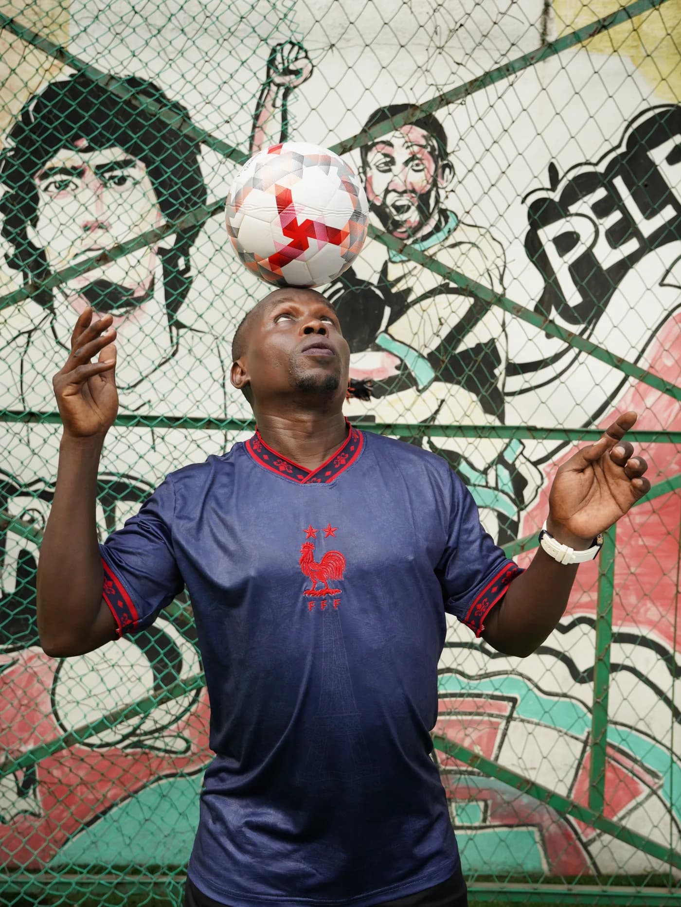 Model heading a ball in the Bleu jersey in front of a Maradona and Pelé mural